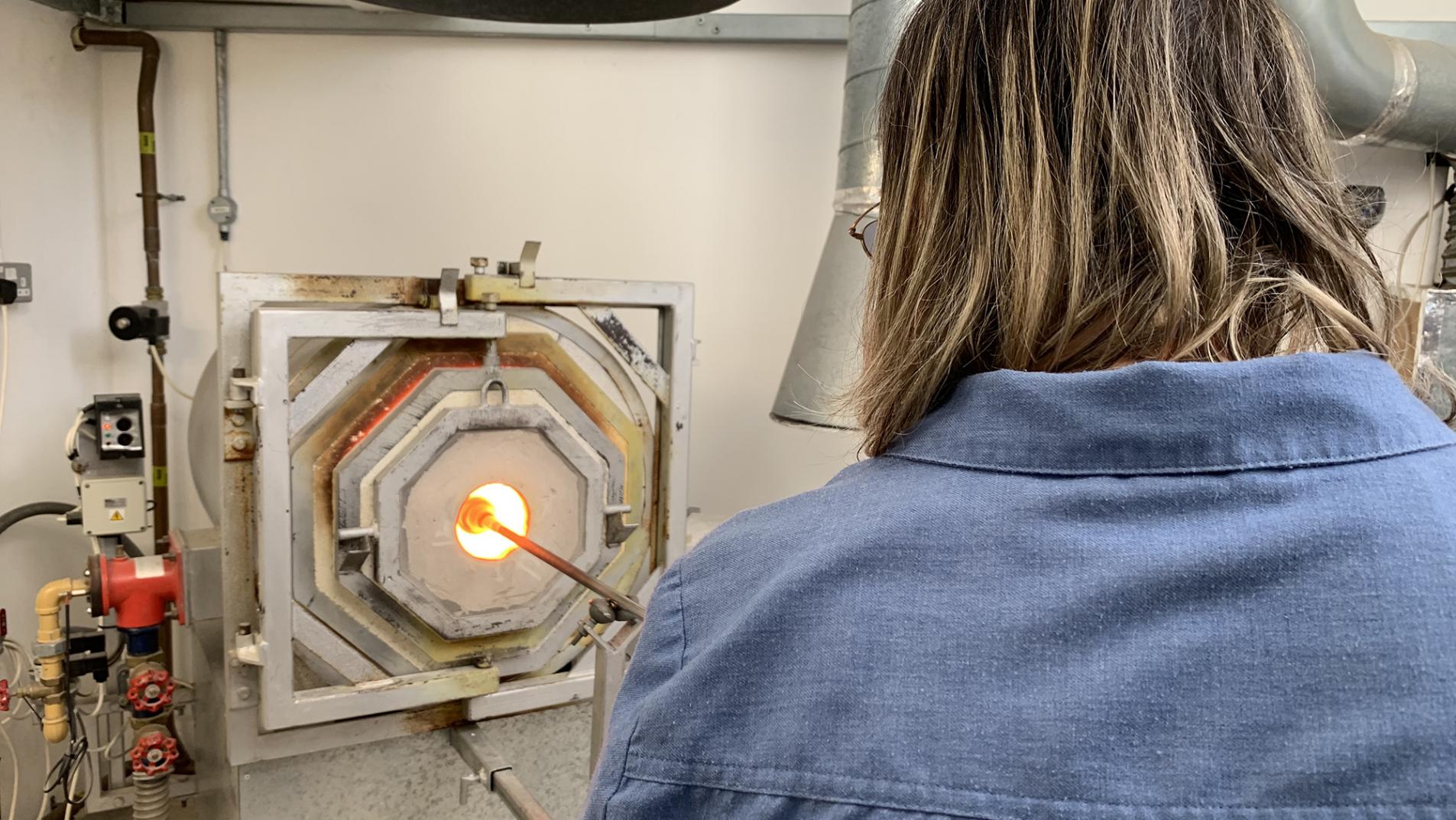 Glassblower shaping glass in a kiln